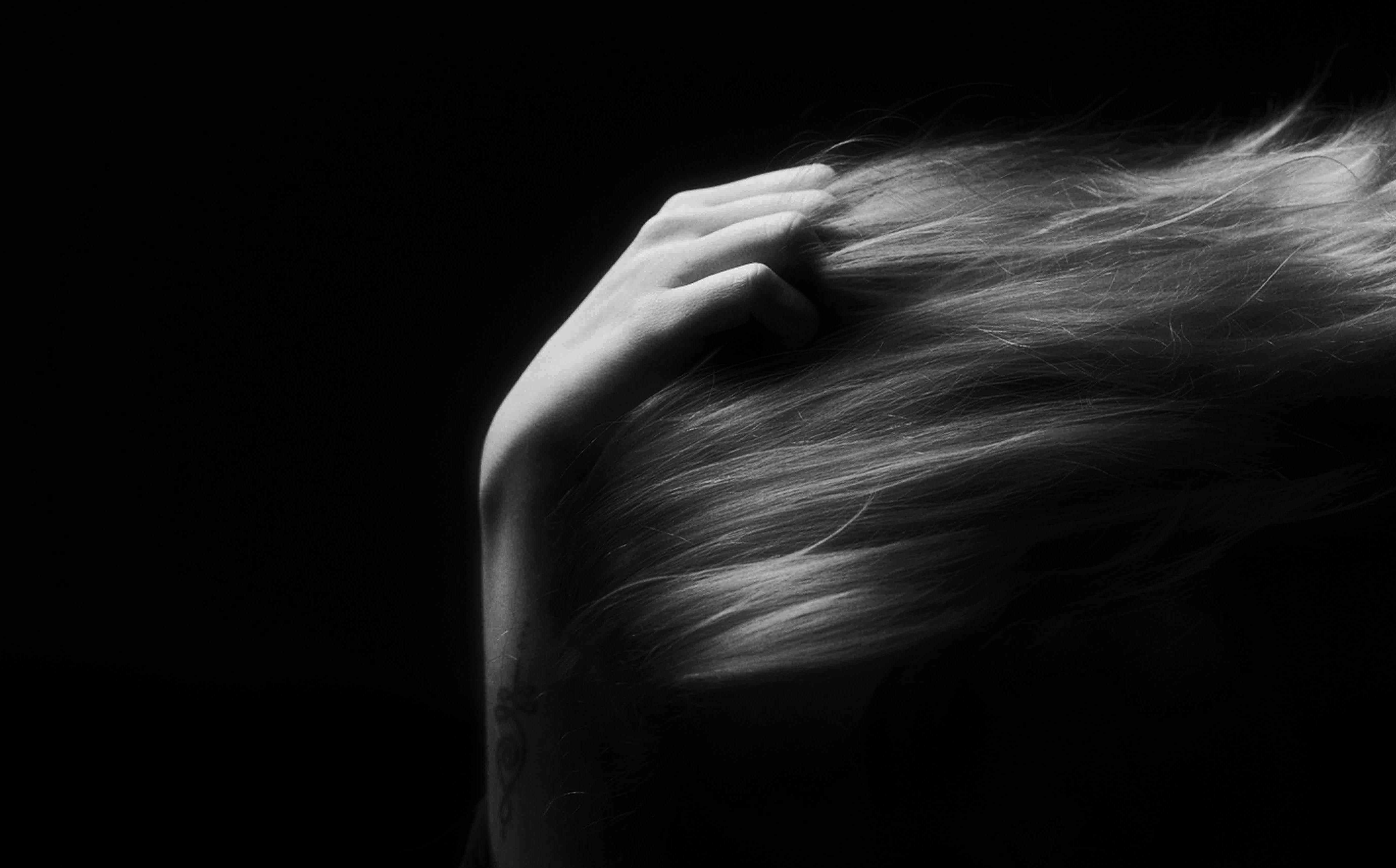 Donna con capelli lunghi e mano sulla testa, fotografia in bianco e nero