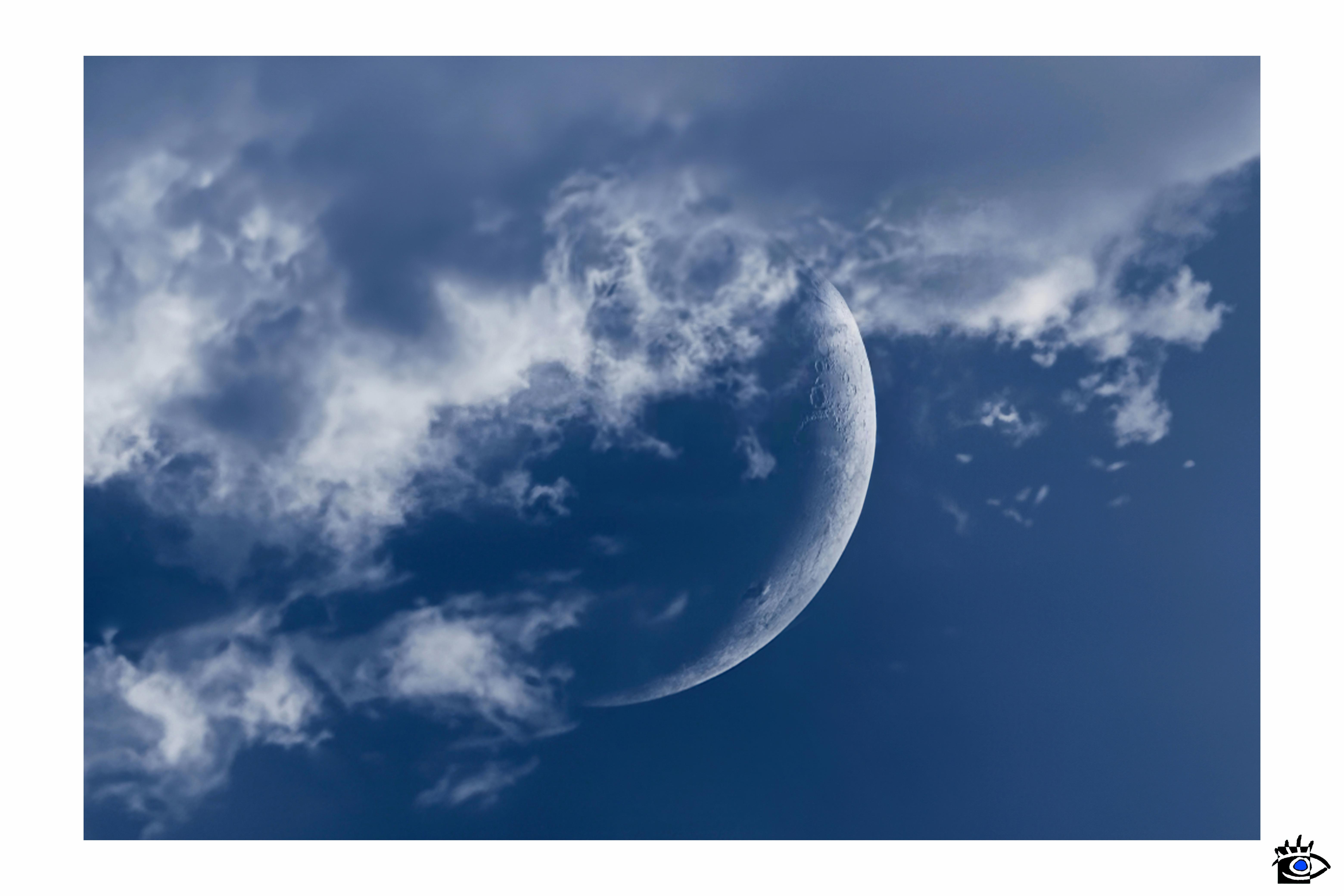 Fotografia della luna alle prime ore del mattino, parzialmente coperta da nuvole mosse dal vento.