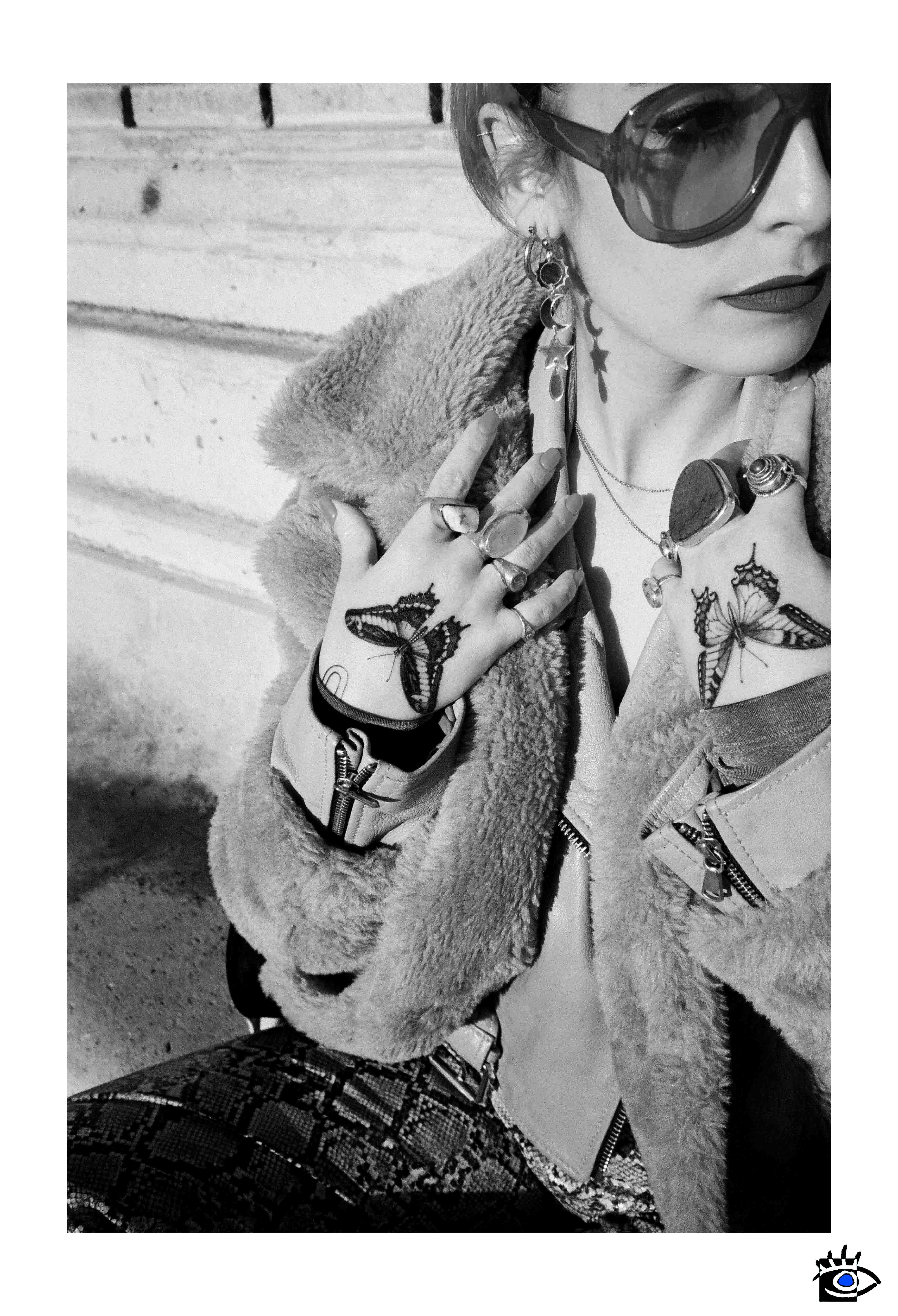 Giovane donna con occhiali da sole, tatuaggi sulle mani e gioielli in un ritratto in bianco e nero, scattato in Piazza Garibaldi a Parma.