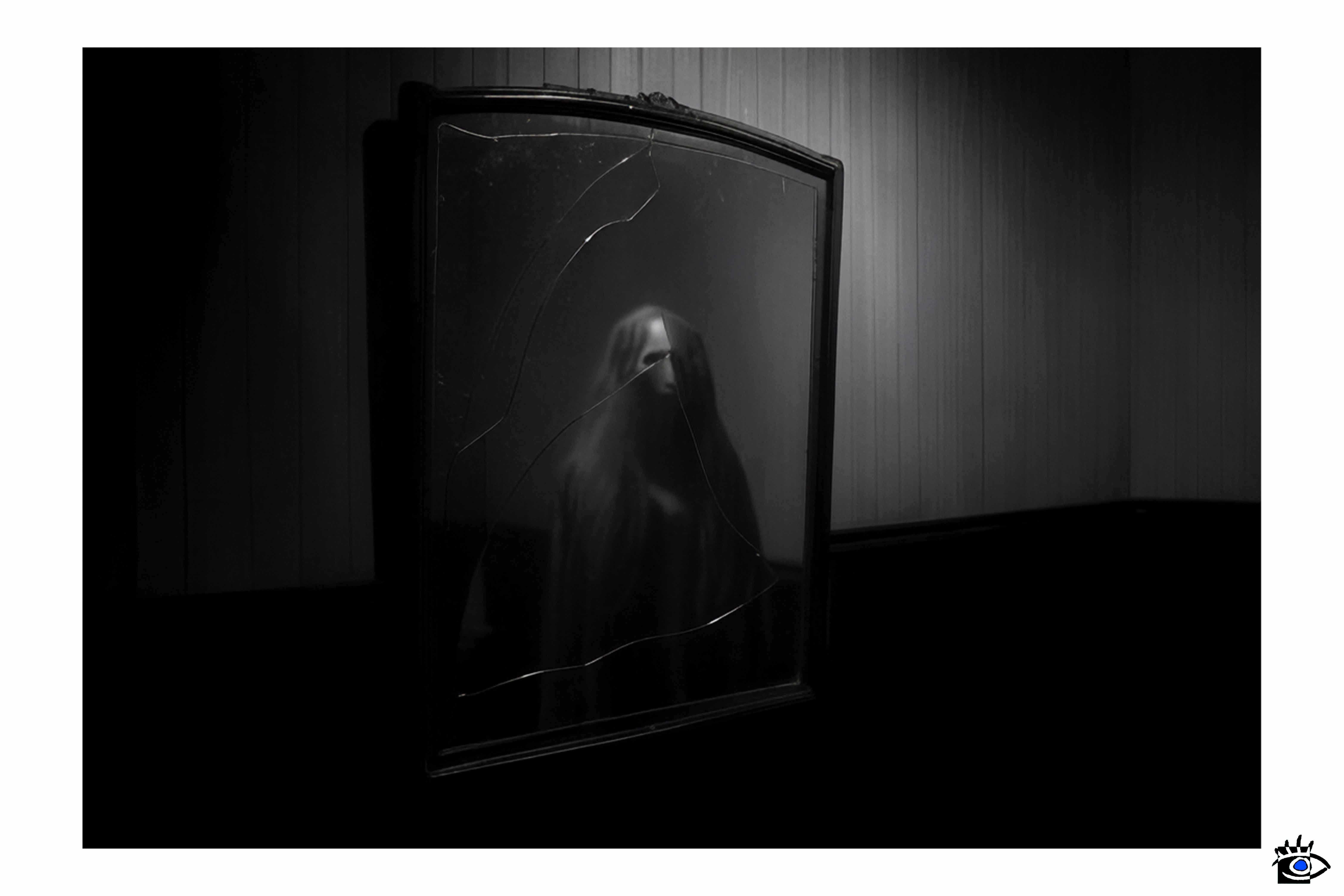 Veiled figure in cracked mirror.