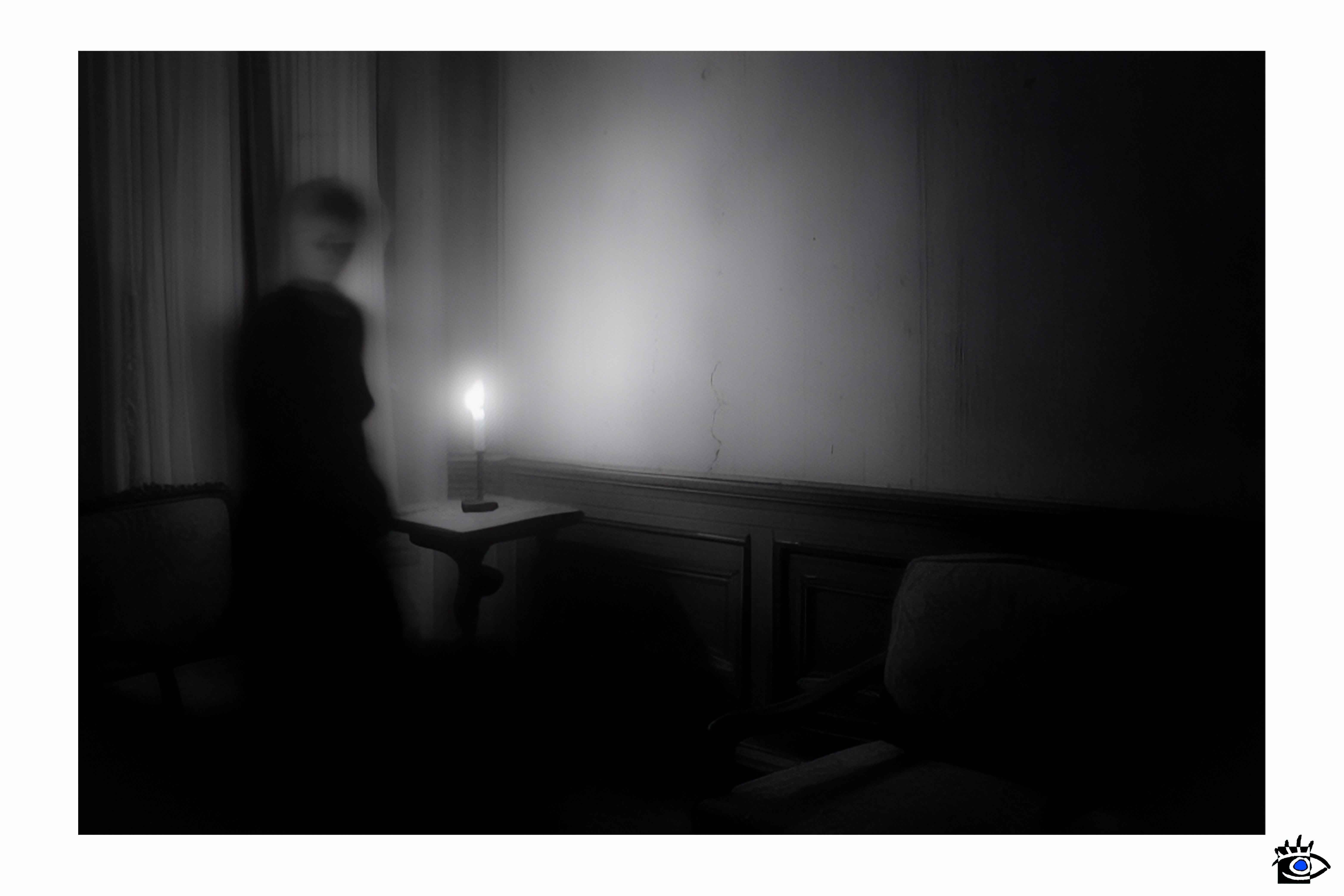 Flickering candle illuminates indistinct figure.