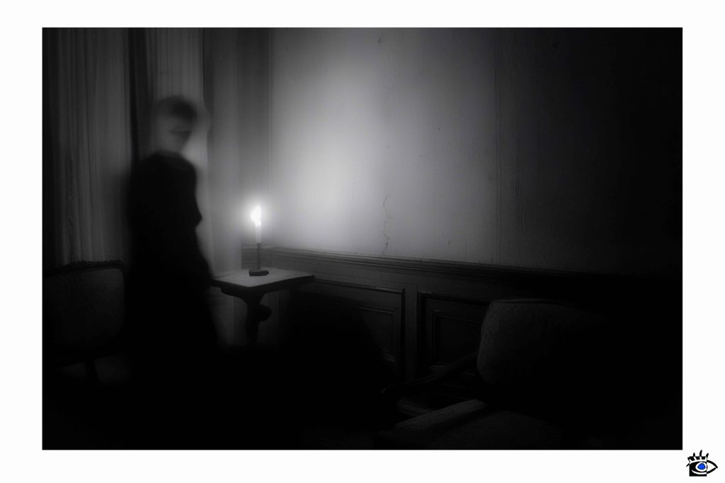 Flickering candle illuminates indistinct figure.