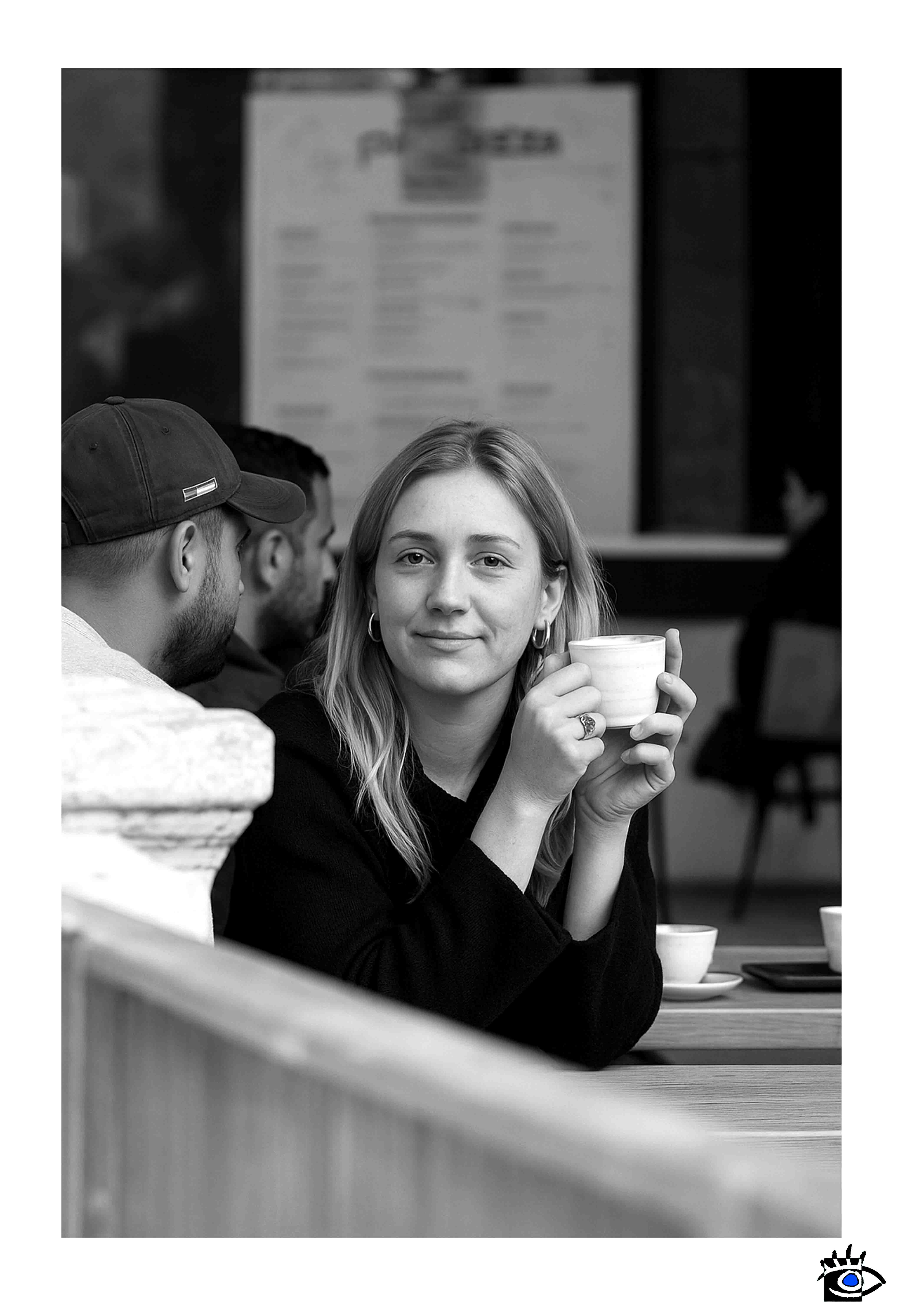 Donna seduta all’aperto tiene una tazza calda tra le mani e guarda verso l’obiettivo con un’espressione tranquilla.